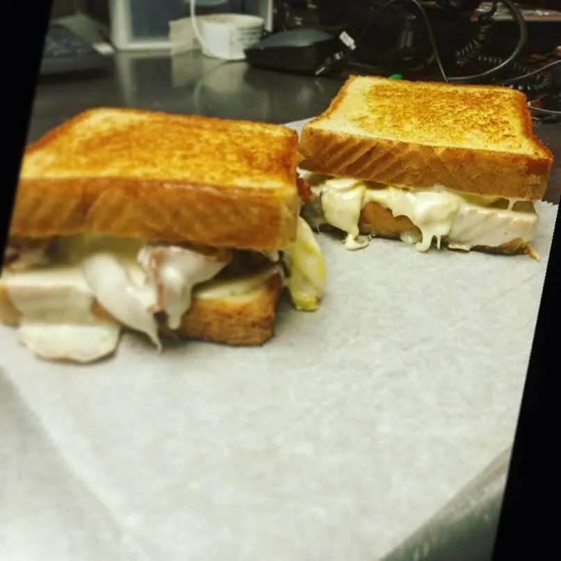 Two grilled cheese sandwiches with melted cheese on a food truck prep counter