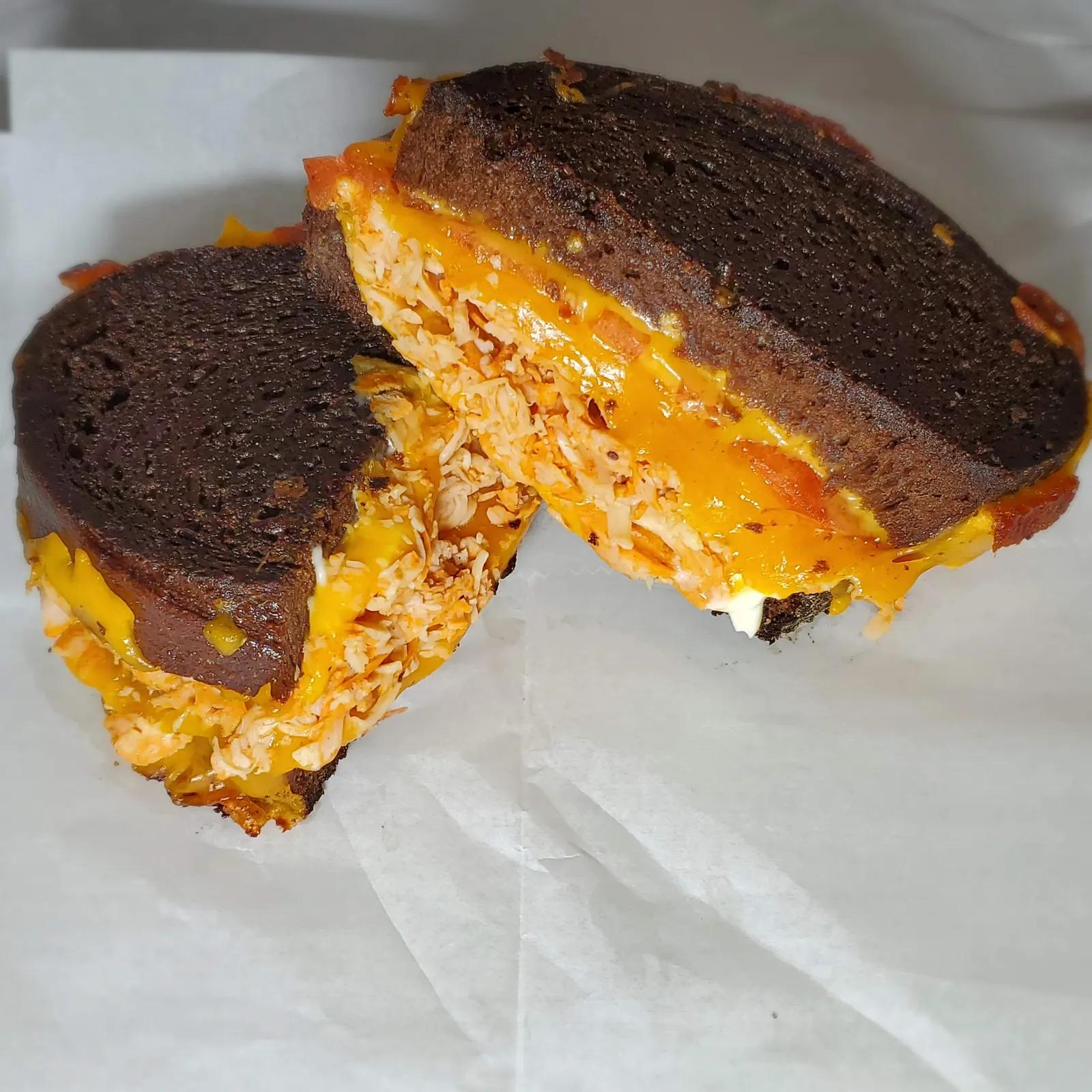 Buffalo chicken grilled cheese with melted cheddar on toasted pumpernickel bread
