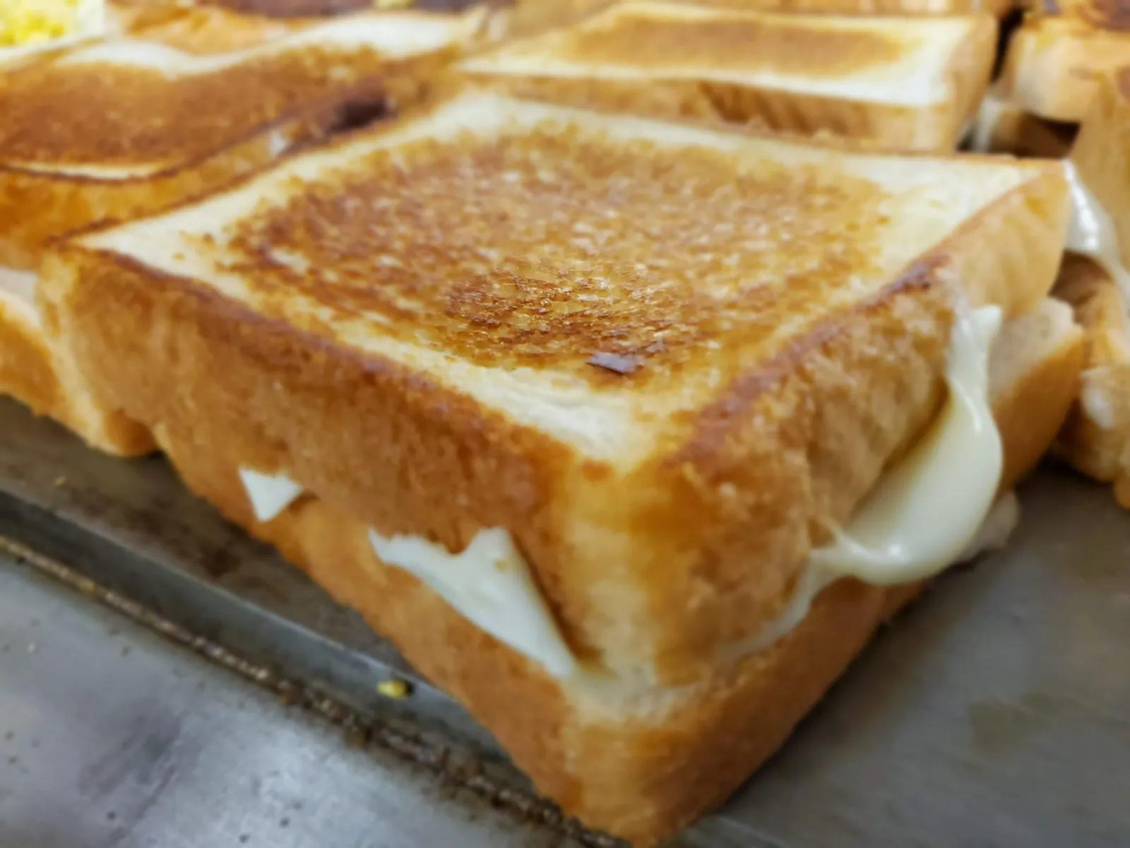 Close-up of a toasted grilled cheese sandwich with melted cheese on the food truck griddle