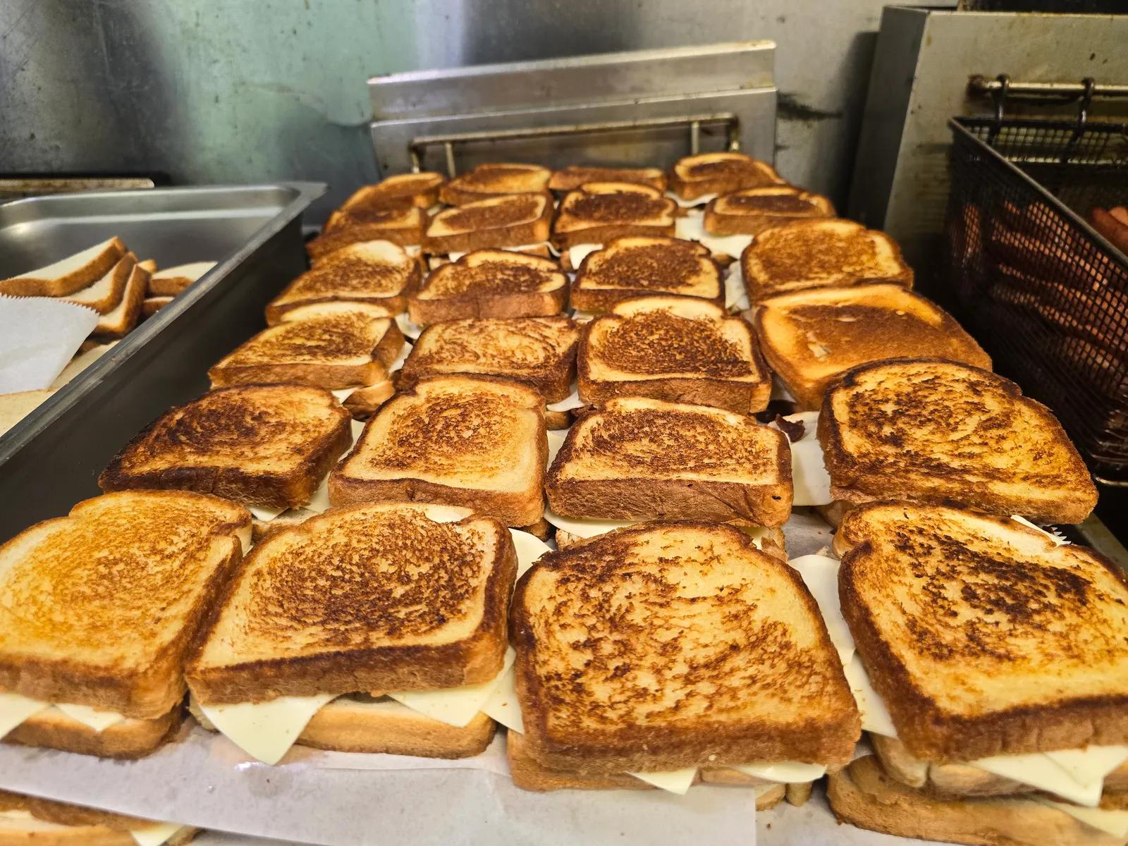 Large tray of golden grilled cheese sandwiches ready for a catered event