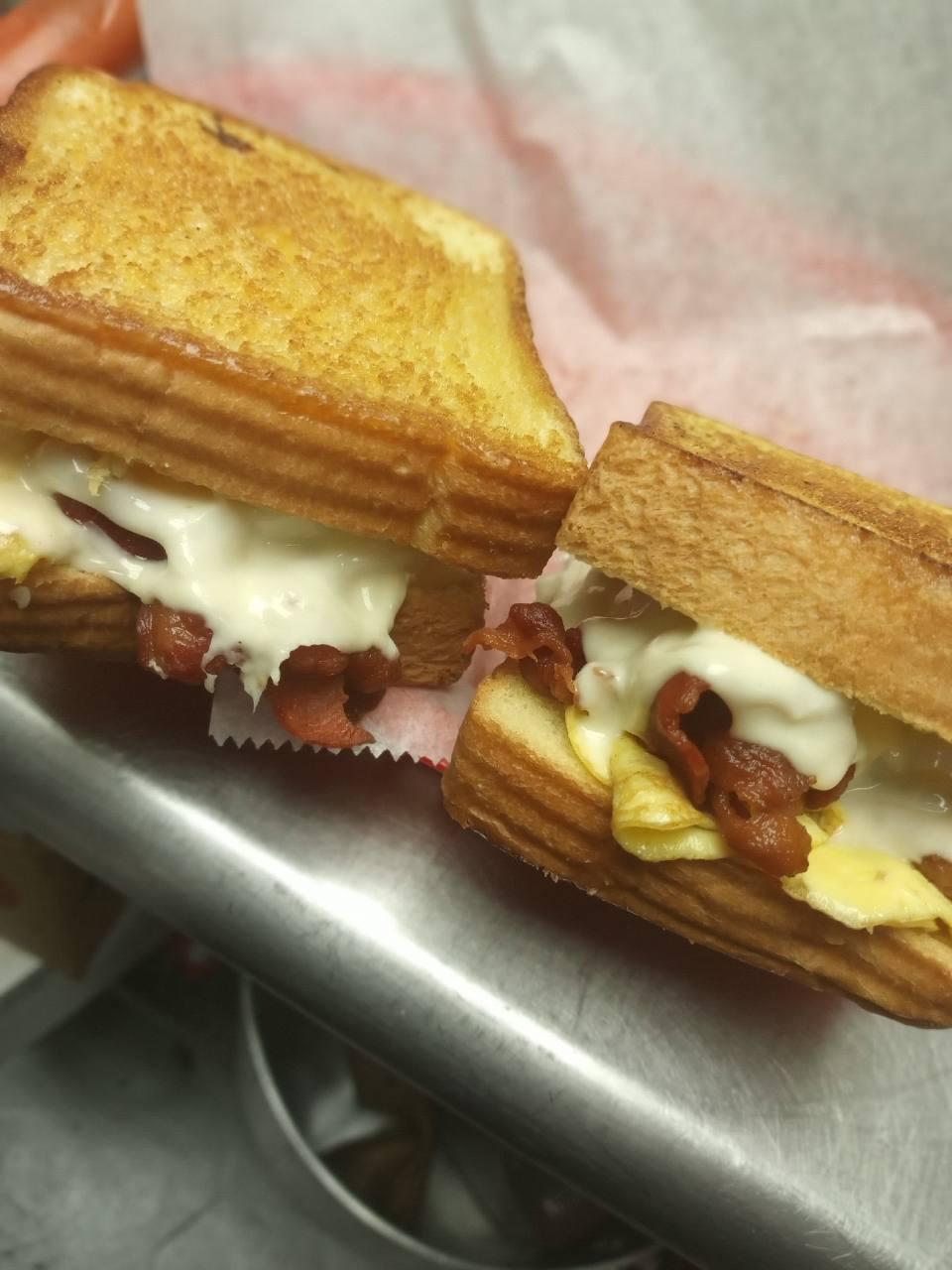 Grilled cheese sandwich halves with bacon and melted cheese
