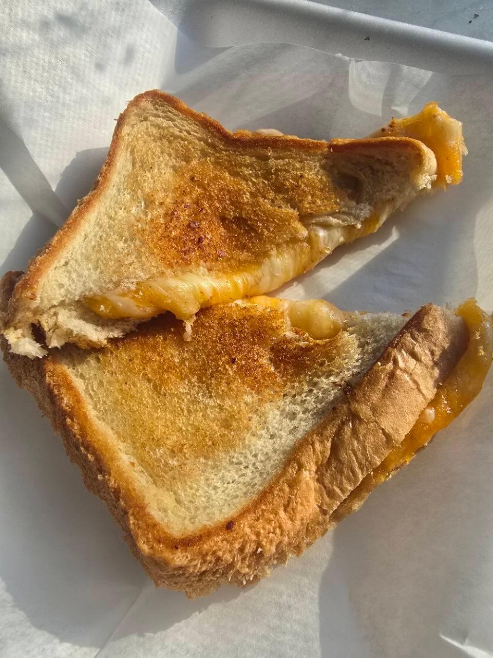 Two grilled cheese sandwich halves on deli paper