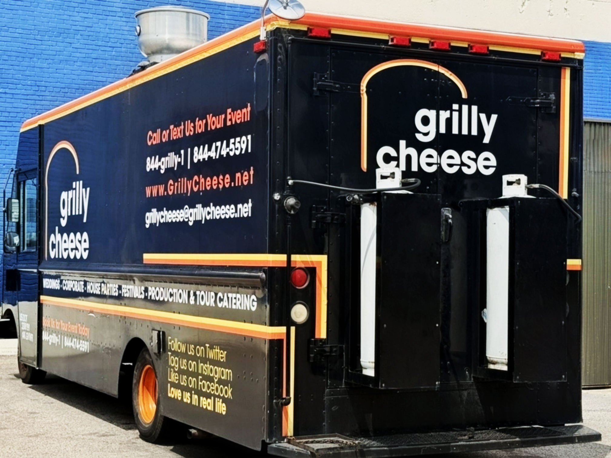Grilly Cheese food truck exterior with black and orange wrap, branding, and contact information