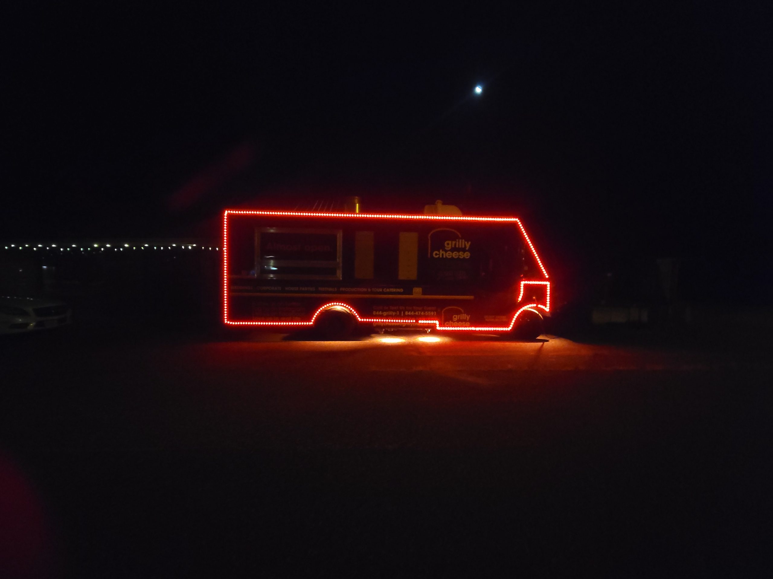 A food truck at nighttime with led lighting strips on the outside of the truck